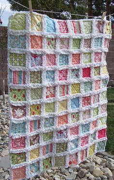 a blanket is hanging on a clothesline in front of some rocks and grass,