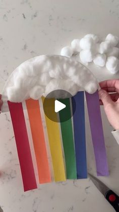 someone is making a paper plate with clouds and rainbows on it in front of a marble counter top