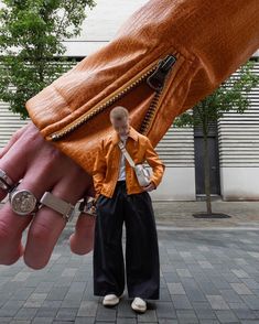 a man standing next to a giant hand with two rings on it's fingers