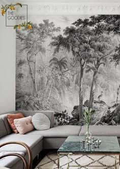 a living room with a couch, coffee table and wall mural on the wall behind it