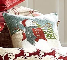 pillows with christmas decorations on them sitting next to a basket filled with presents and gifts