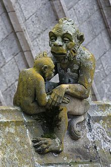 a statue of two monkeys sitting on top of a stone wall next to each other