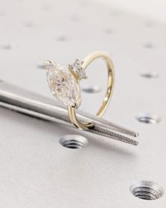 a diamond ring sitting on top of a piece of metal next to some screwdrivers