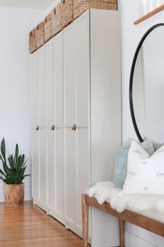 a room with white cupboards and a mirror on the wall next to a wooden bench