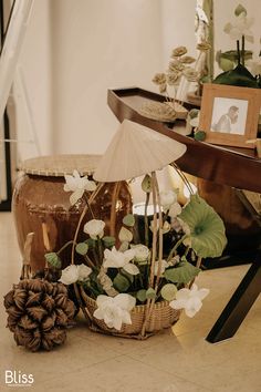 a basket filled with white flowers next to a pine cone on the floor near other items