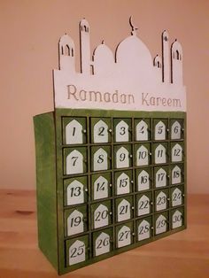 a wooden calendar sitting on top of a table in front of a wall with a clock