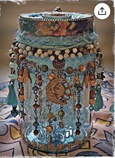 a glass jar filled with lots of different beads and chains on top of a table