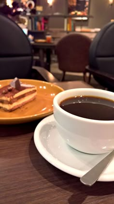 a cup of coffee sits on a saucer next to a plate with some cake