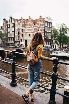 a woman standing on a bridge looking at the water