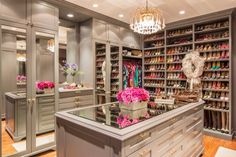 a walk in closet with chandelier and pink flowers on the counter, along with shoes