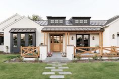 a white house with black shutters and wood accents on the front door is shown