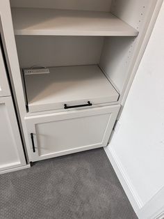 an empty white cabinet in a room with carpeted flooring and gray rugs