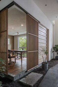 an open door leading to a dining room and living room with wood slats on the walls