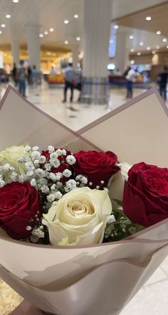 a bouquet of red and white roses in a paper wrapper at an airport terminal