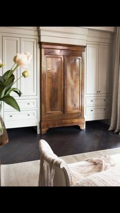 a bedroom with white cabinets and flowers in a vase on the floor next to a bed