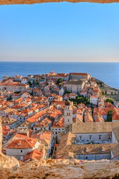 an aerial view of a city with red roofs and the ocean in the back ground