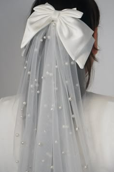 the back of a woman's head wearing a white veil with pearls on it