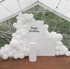 a birthday party with white balloons and a happy birthday sign