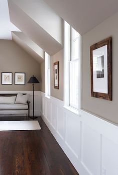 a living room filled with furniture and framed pictures on the wall next to a wooden floor