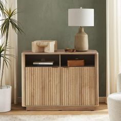 a living room with green walls and a wooden cabinet next to a white chair in front of a lamp