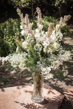 a vase filled with lots of white flowers on top of a stone slab in the grass