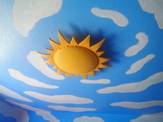 a sun painted on the ceiling in a child's room with clouds and blue sky