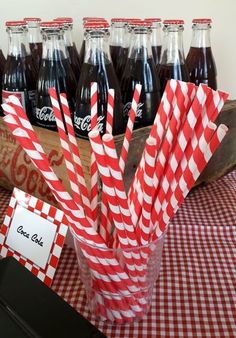 there are many coca colas in the glass on the table with red and white paper straws