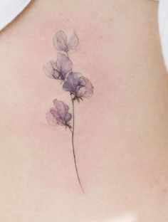 the back of a woman's stomach with purple flowers on her left side ribcage