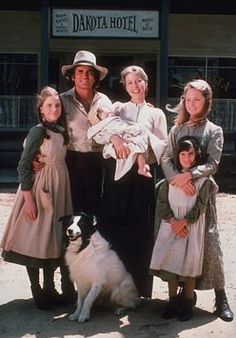 a family poses for a photo in front of the dakota hotel with their dog and child