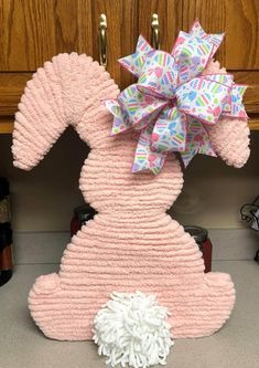 a pink stuffed animal with a big bow on it's head sitting in front of a cabinet