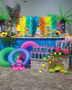 an assortment of colorful balloons and decorations on the ground in front of a party table