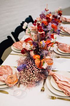 the table is set with plates, silverware and flowers