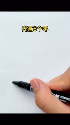 a person holding a pen in their left hand and writing on paper with chinese characters