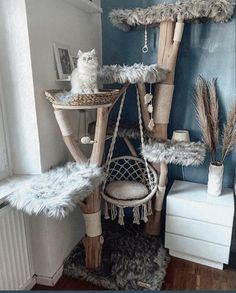 a cat tree in the corner of a room with blue walls and white furniture, including a hammock chair