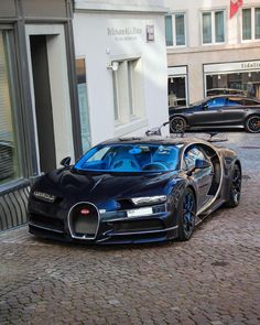 two bugatti cars parked on the street in front of a building with people walking by