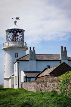 a white lighthouse sitting on top of a lush green hillside