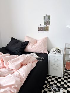 a black and white checkered floor in a bedroom with pink sheets on the bed