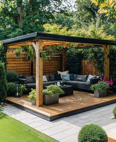 an outdoor living area with couches and potted plants on the deck, surrounded by greenery