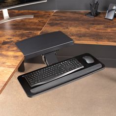 a computer keyboard sitting on top of a wooden desk next to a mouse and monitor