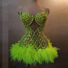 a mannequin wearing a green dress with sequins and feathers on it