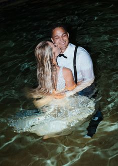 a man and woman are kissing in the water while they sit on a surfboard