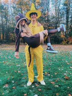 a man and woman dressed up in costumes posing for a photo on the grass with leaves all around them