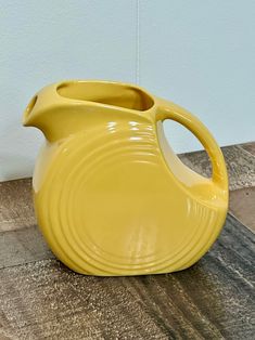 a yellow vase sitting on top of a wooden table