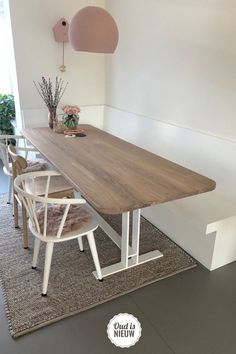 a wooden table with white chairs in a room