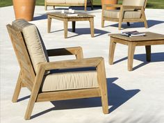 a group of wooden chairs and tables sitting on top of a cement ground next to plants