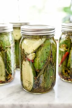 several jars filled with pickles sitting on top of a counter