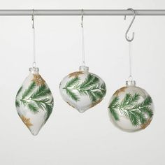 three christmas ornaments hanging from a metal bar with white and green decorations on it's sides