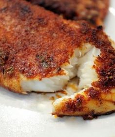 a piece of fish that is on a plate with some seasoning sprinkles