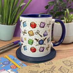 a coffee mug sitting on top of a wooden table next to potted plants and scissors