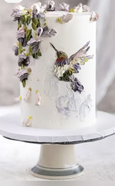 a white cake decorated with flowers and hummings